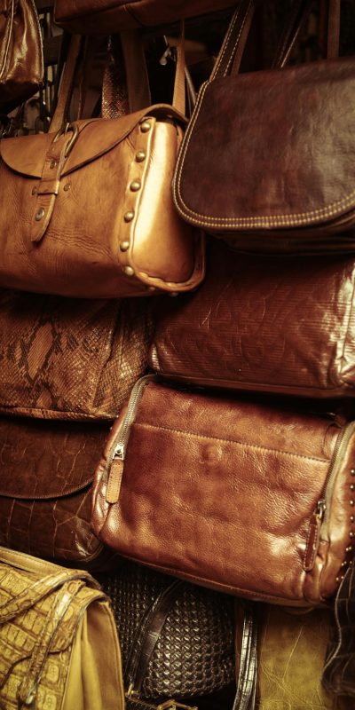 A collection of vintage leather bags in various styles and colors showcased in a market stall.